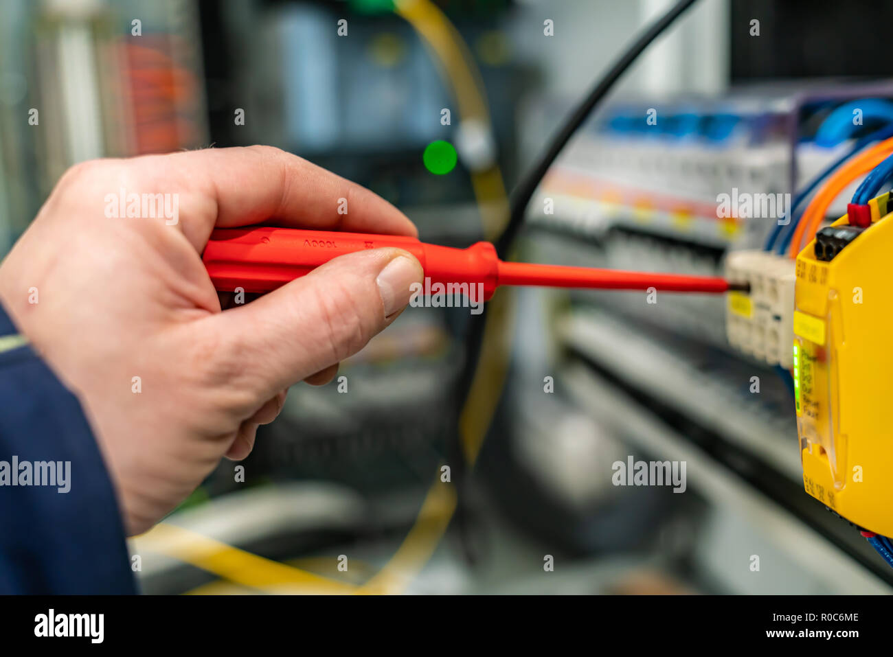Primo piano di una mano con un cacciavite le opere in un armadio di controllo Foto Stock