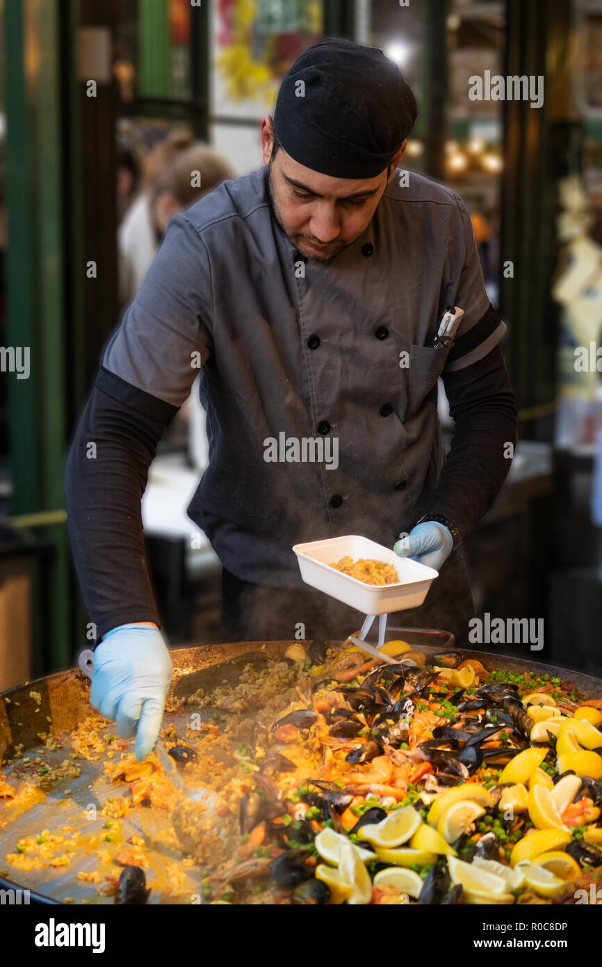 Lo chef serve piatti di pesce Paella in London Borough Market Foto Stock