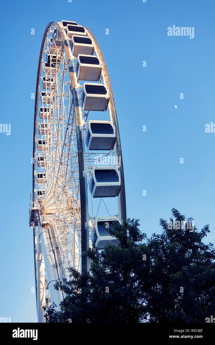 Ruota panoramica Ferris e luna su un cielo blu di sfondo blu all'ora. Basso angolo verticale di sparare. Foto Stock