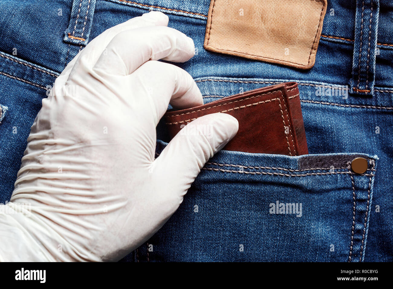 Ladro indossando un vinile bianco guanto ruba il portafoglio dalla tasca  posteriore dei jeans. Vista ravvicinata di borseggio Foto stock - Alamy