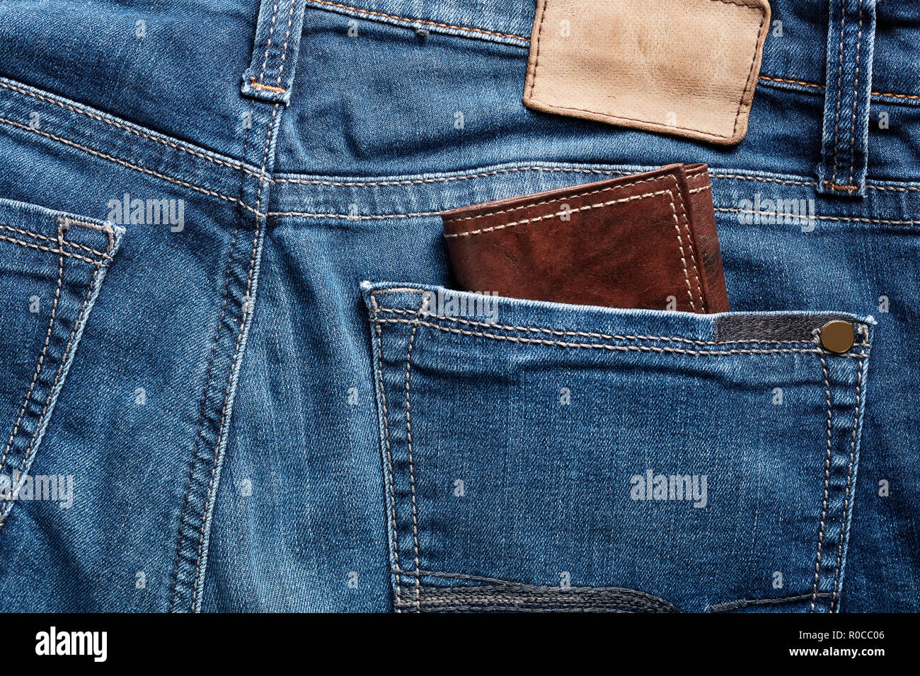 Pelle marrone portafoglio nella tasca posteriore di un'indigo blue jeans Foto Stock