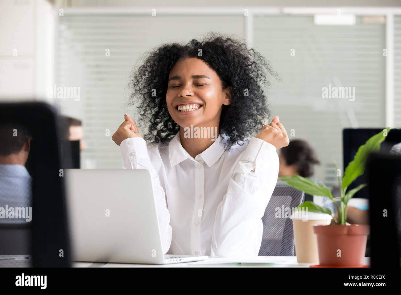 Emozionato africana di lavoratore di ufficio riceve una buona notizia in un messaggio di posta elettronica su la Foto Stock