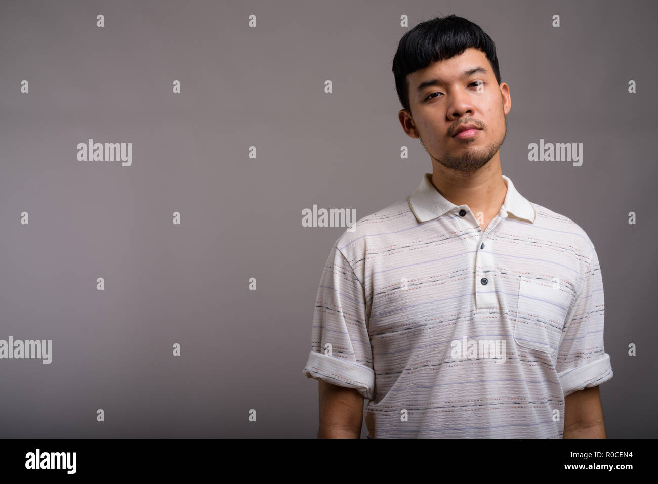 Ritratto di giovane uomo asiatico contro uno sfondo grigio Foto Stock