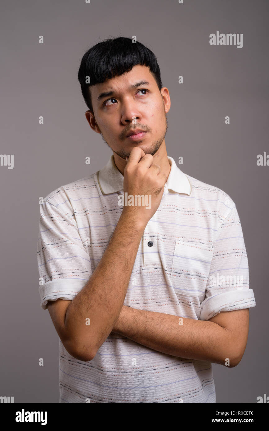 Ritratto di giovane uomo asiatico pensando e progettando Foto Stock