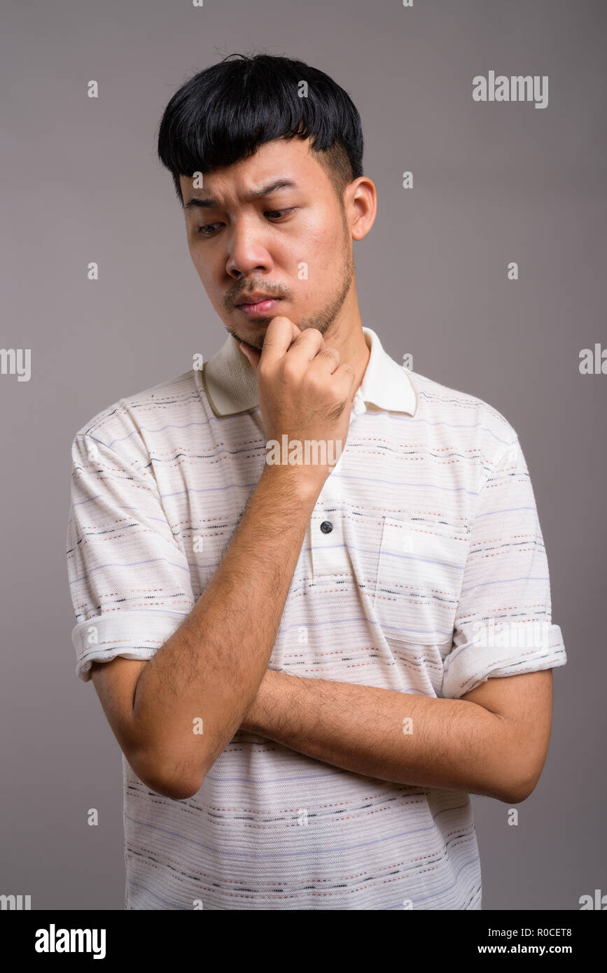 Ritratto di giovane uomo asiatico pensando e progettando Foto Stock