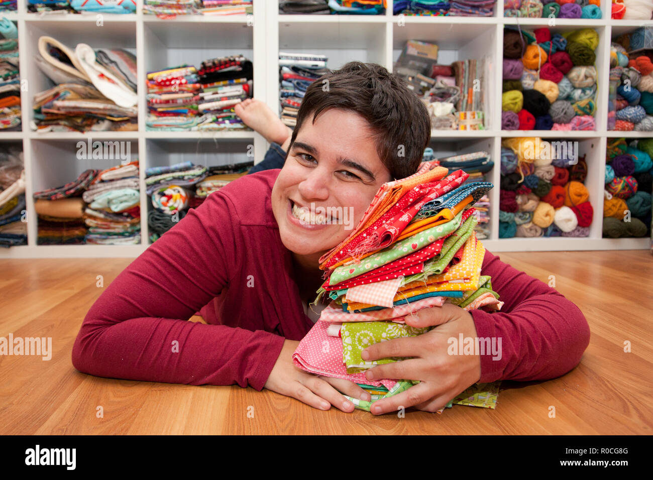 Donna getta sul Suo palo di coloratissimi fat quarters nel suo spazio di artigianato Foto Stock