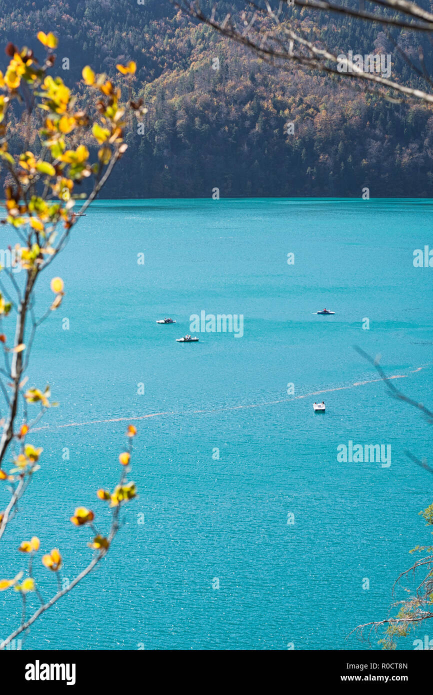 Vista sul lago color turchese "Alpsee" con pedalò su di esso in una calda giornata di sole in autunno. Hohenschwangau, Füssen, Baviera, Germania Foto Stock