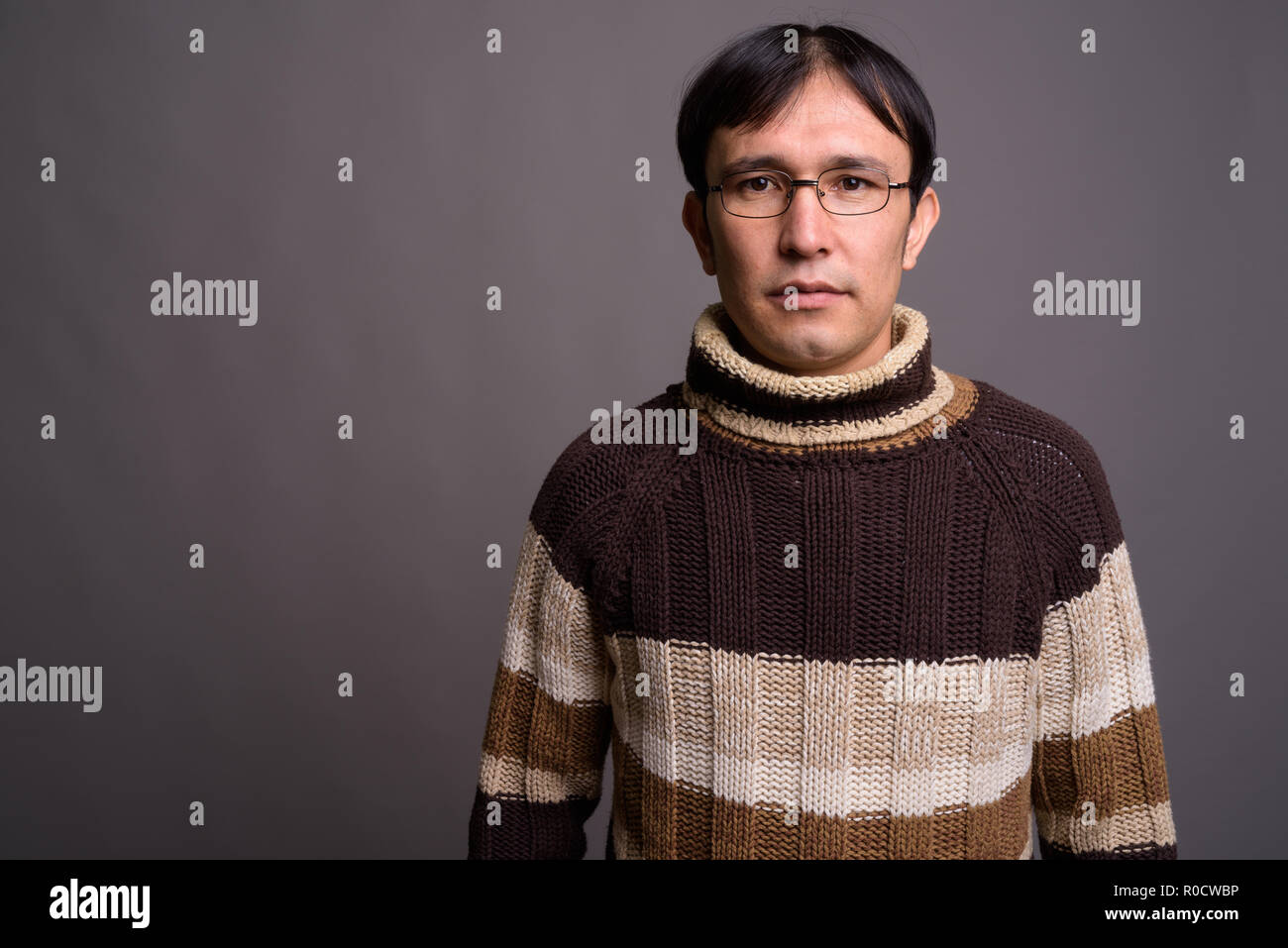 Giovani asiatici nerd uomo turtleneck indossa un maglione grigio contro bac Foto Stock