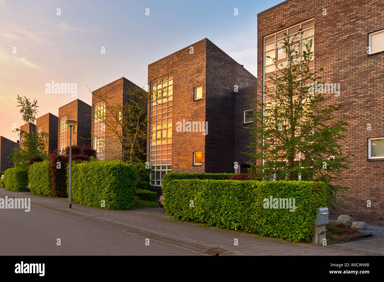 Quartiere con case moderne in una strada suburbana nel sole del pomeriggio Foto Stock