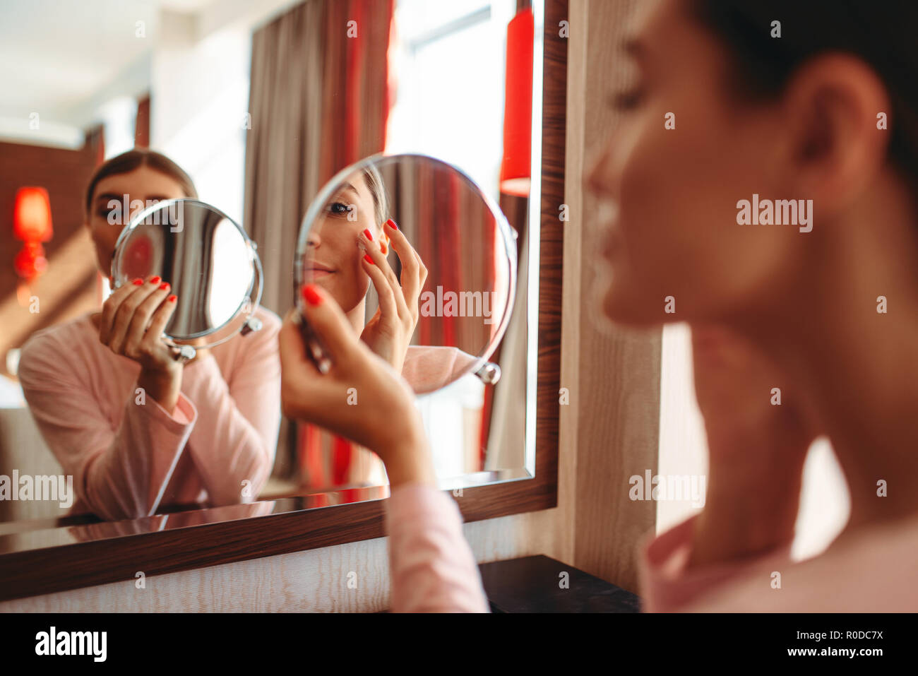 Giovane donna fare il trucco davanti allo specchio in camera da letto.  Persona di sesso femminile si prende cura della pelle. Mattina viso igiene  Foto stock - Alamy