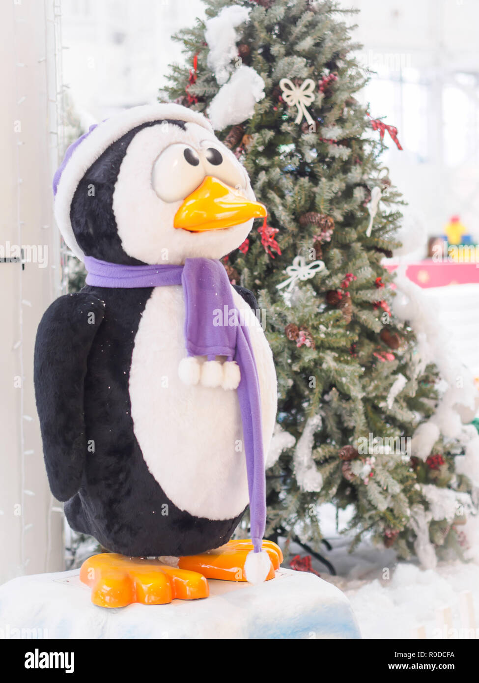 Un pinguino giocattolo in piedi contro gli alberi di Natale circondato con confezioni regalo. Natale e Anno Nuovo concetto. Foto Stock