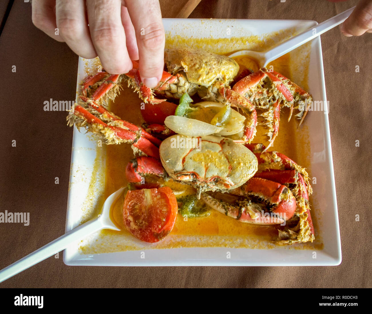 Una persona degusting con le mani un delizioso piatto tipico di granchio con pomodoro e salsa di cipolla e altre spezie in Jacare beach, nella città di Joao Foto Stock