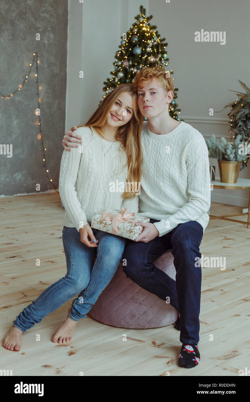 Bella felice coppia giovane seduti insieme e sorridente in telecamera alla vigilia di Natale Foto Stock