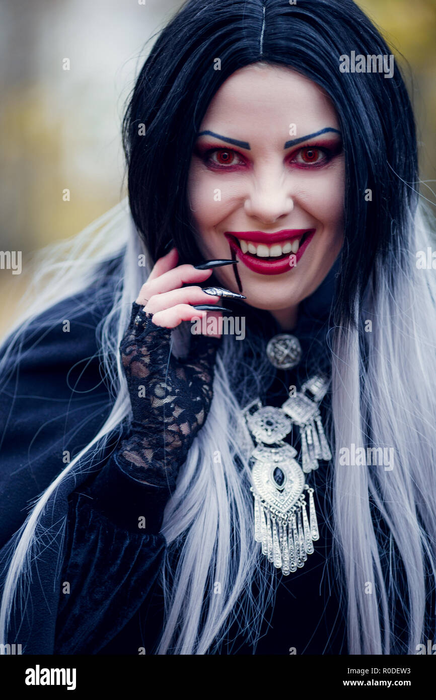Immagine di sorridente vampiro femmina con il flusso di sangue in prossimità della bocca Foto Stock