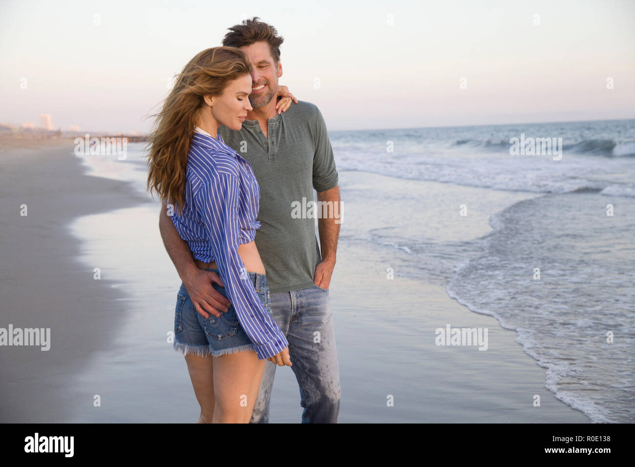 Lunghezza Three-Quarter ritratto della coppia Mid-Adult permanente al Beach Foto Stock