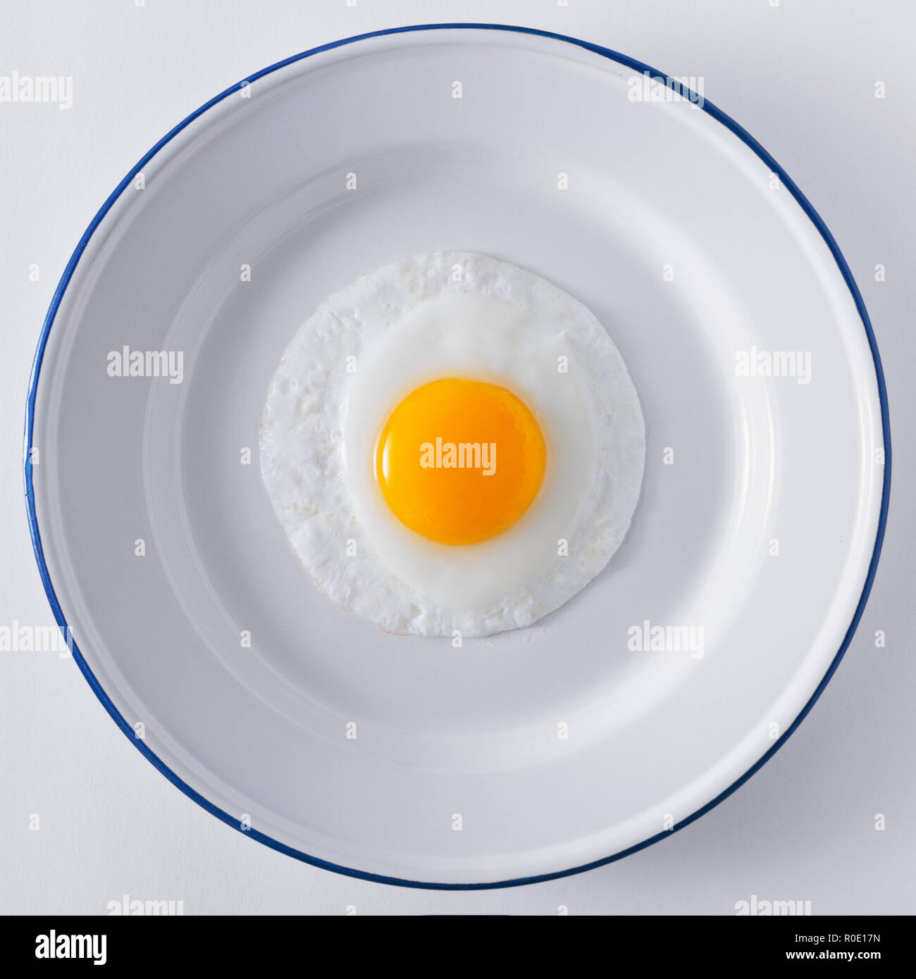Angolo di Alta Vista Sunny-Side fino uovo sulla piastra bianca con cerchio blu Foto Stock