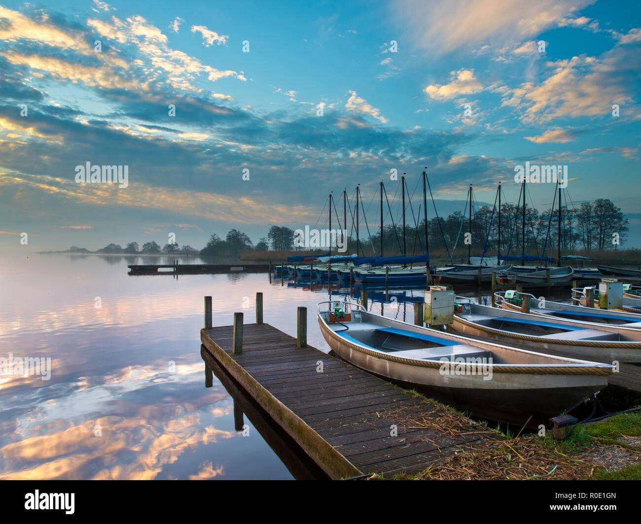 Huurboten liggen tijdens zonsopkomst aan de kade van een meer, Klaar voor een nieuwe dag. Foto Stock