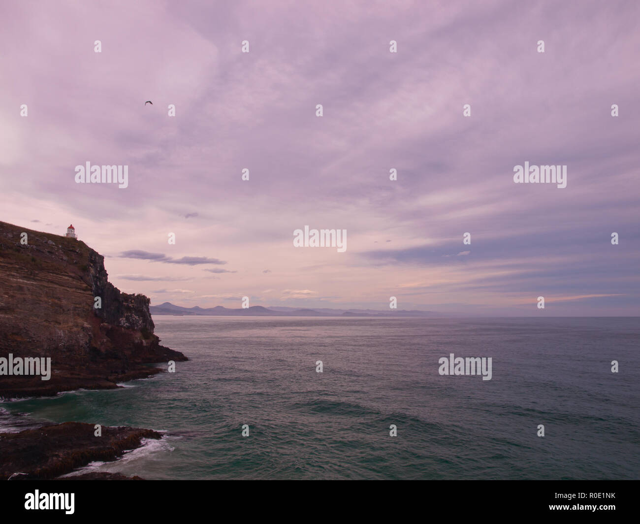 Un faro in remoto su una roccia che si affaccia l'infinito oceano Foto Stock