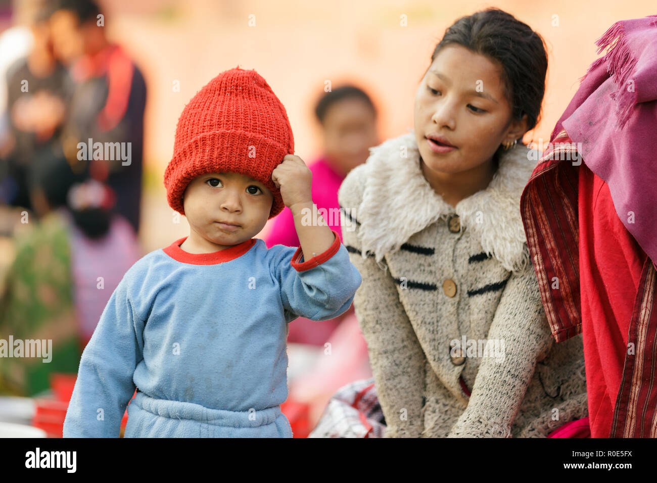 KATHMANDU, NEPAL,Novembre 04,2010: un piccolo ragazzo che indossa un rosso cappellino è in posa al mercato di strada nel centro storico di Patan Durbar Square a Kathma Foto Stock