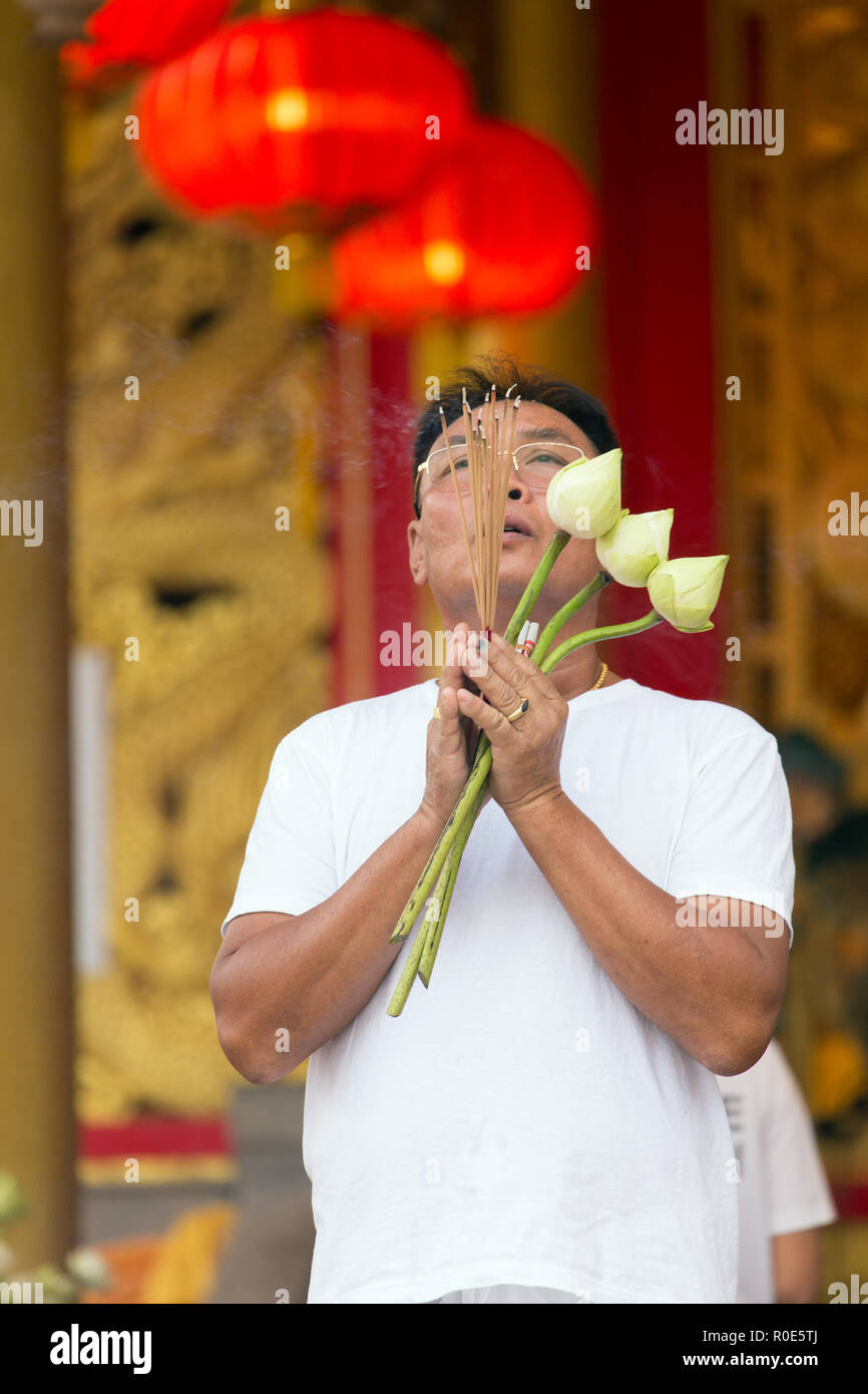 Città di Phuket, Thailandia, 05 Ottobre 2016 : un uomo sta pregando, tenendo i fiori di loto e bastoncini di incenso in Sapha Hin Santuario della città di Phuket, Tailandia Foto Stock