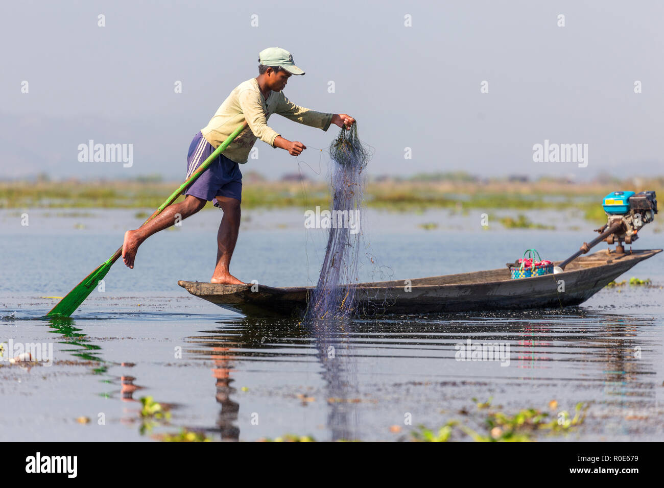 Lago Inle, Myanmar, gennaio 26, 2015 : un pescatore che mostra la tecnica speciale di canottaggio la tradizione birmana utilizzando la sua gamba per la manipolazione della racchetta Foto Stock