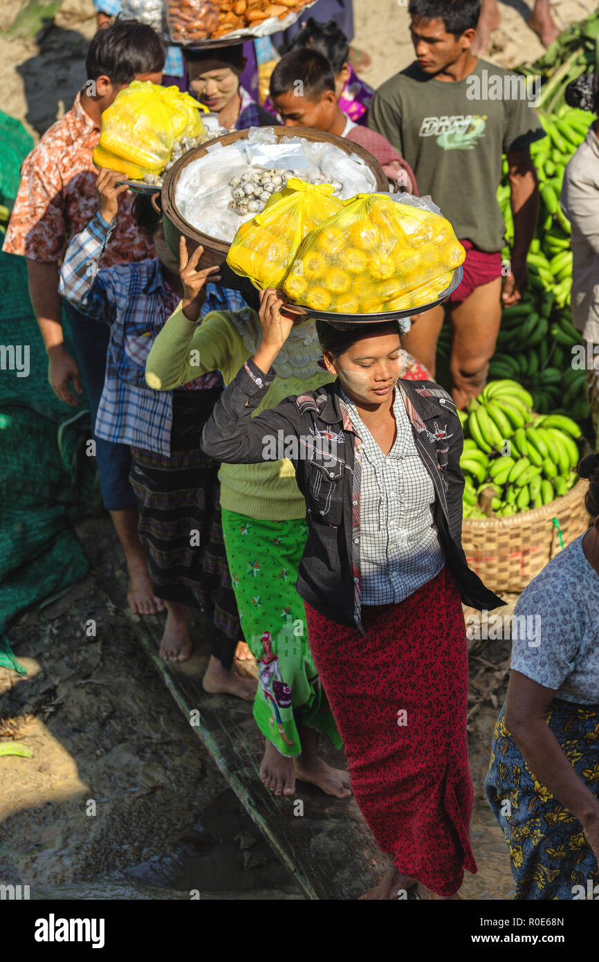 MANDALAY, Myanmar, gennaio 21, 2015 : donne birmane sono di salire a bordo di un battello a camminare su una trave di legno, portando le verdure sulle loro teste a Mandalay, Foto Stock