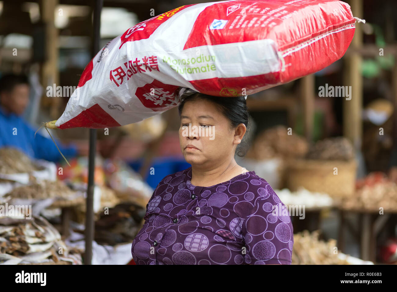 MANDALAY,MYANMAR,17 Gennaio 2015 : Una donna sta portando una grande glutammato monosodico sacco sul suo capo in strada di Mandalay, Myanmar (Birmania). Foto Stock