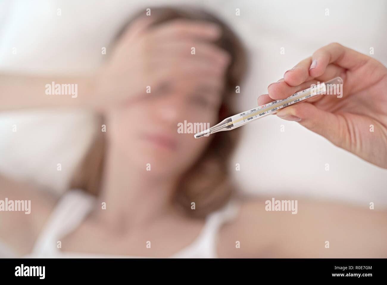 Giovane donna prendendo la sua temperatura. Foto Stock