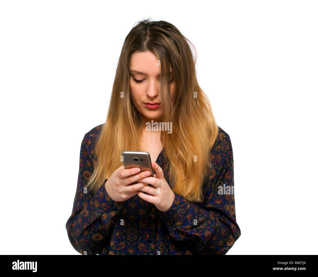 Giovane donna utilizza lo smartphone contro uno sfondo bianco. Foto Stock