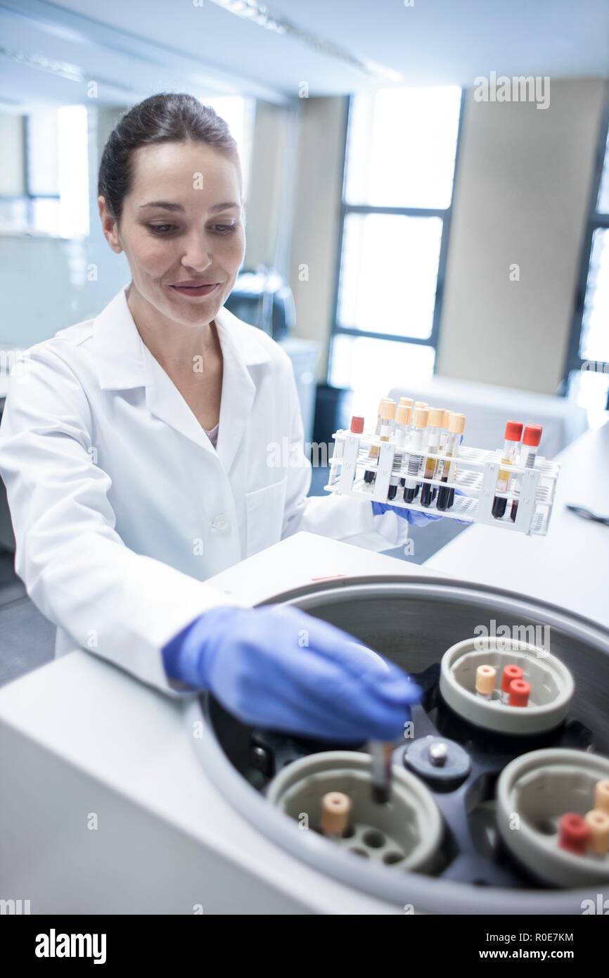 Femmina assistente di laboratorio utilizzando macchina centrifuga. Foto Stock