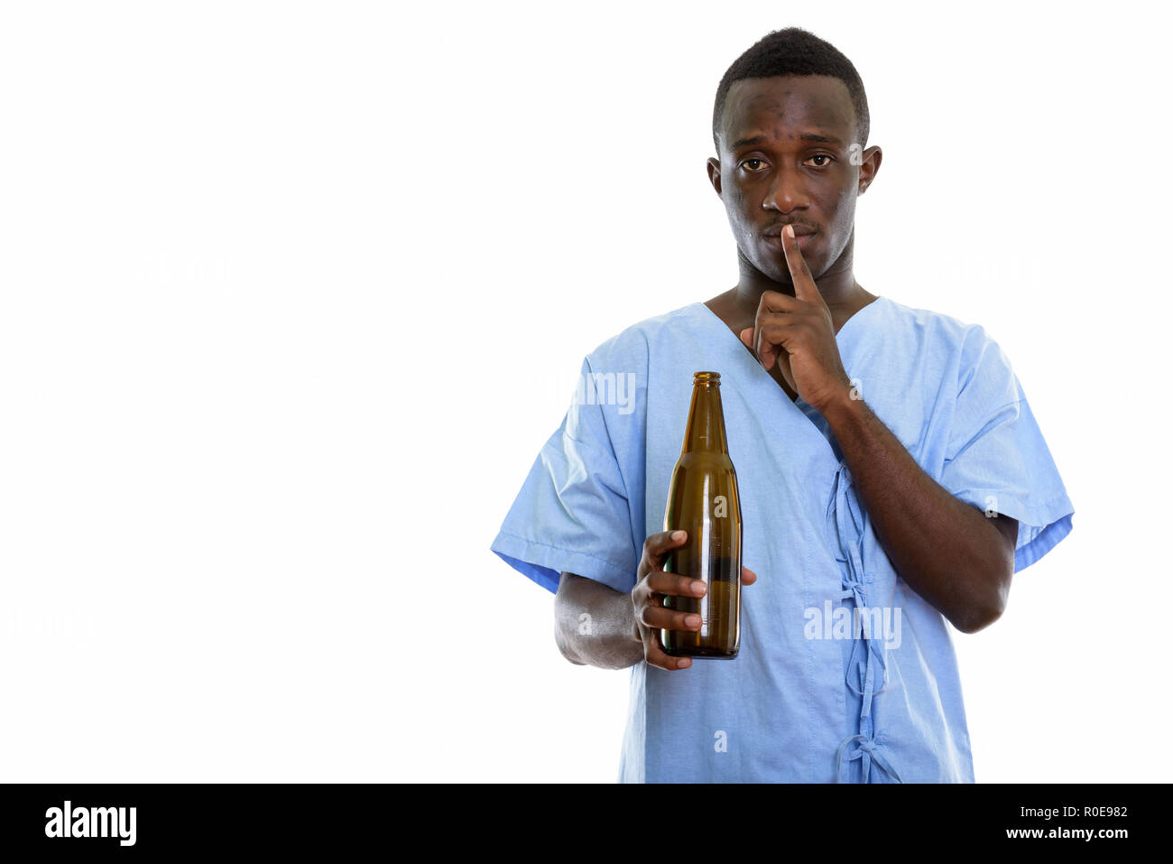 Studio shot del giovane africano nero uomo paziente tenendo una bottiglia di Foto Stock