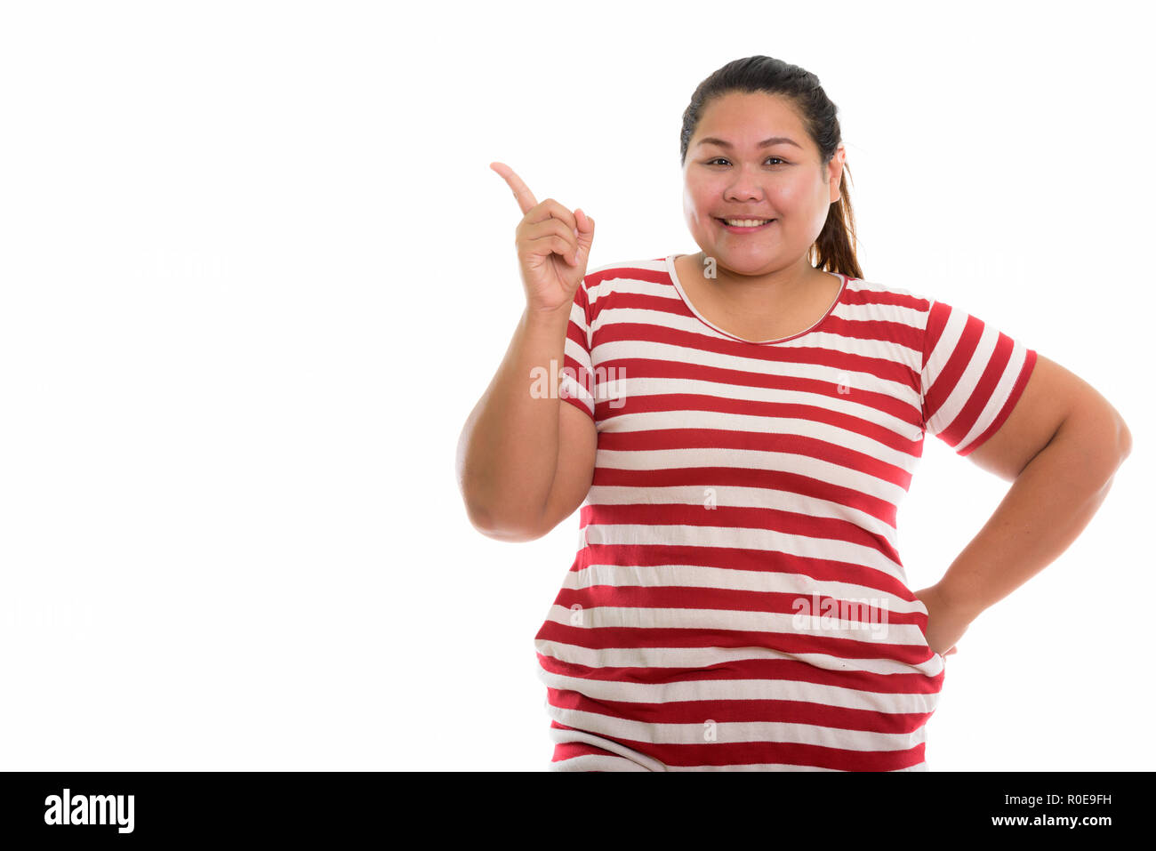 Studio shot di giovani felici fat donna asiatica sorridere mentre pointin Foto Stock