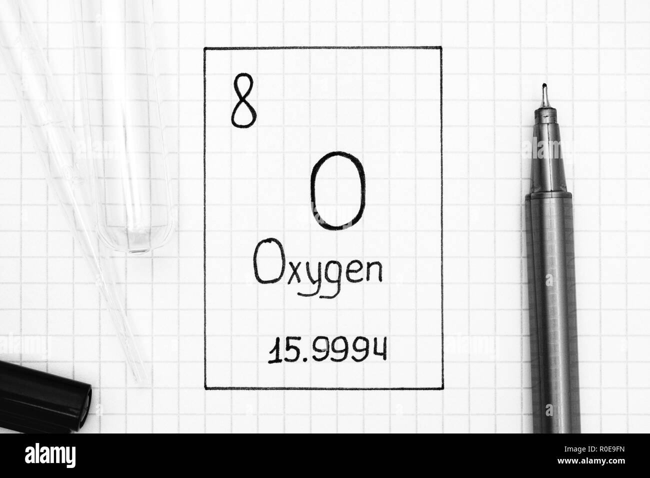 Tavola periodica degli elementi. La grafia elemento chimico di ossigeno o con la penna nera, tubo di prova e la pipetta. Close-up. Foto Stock