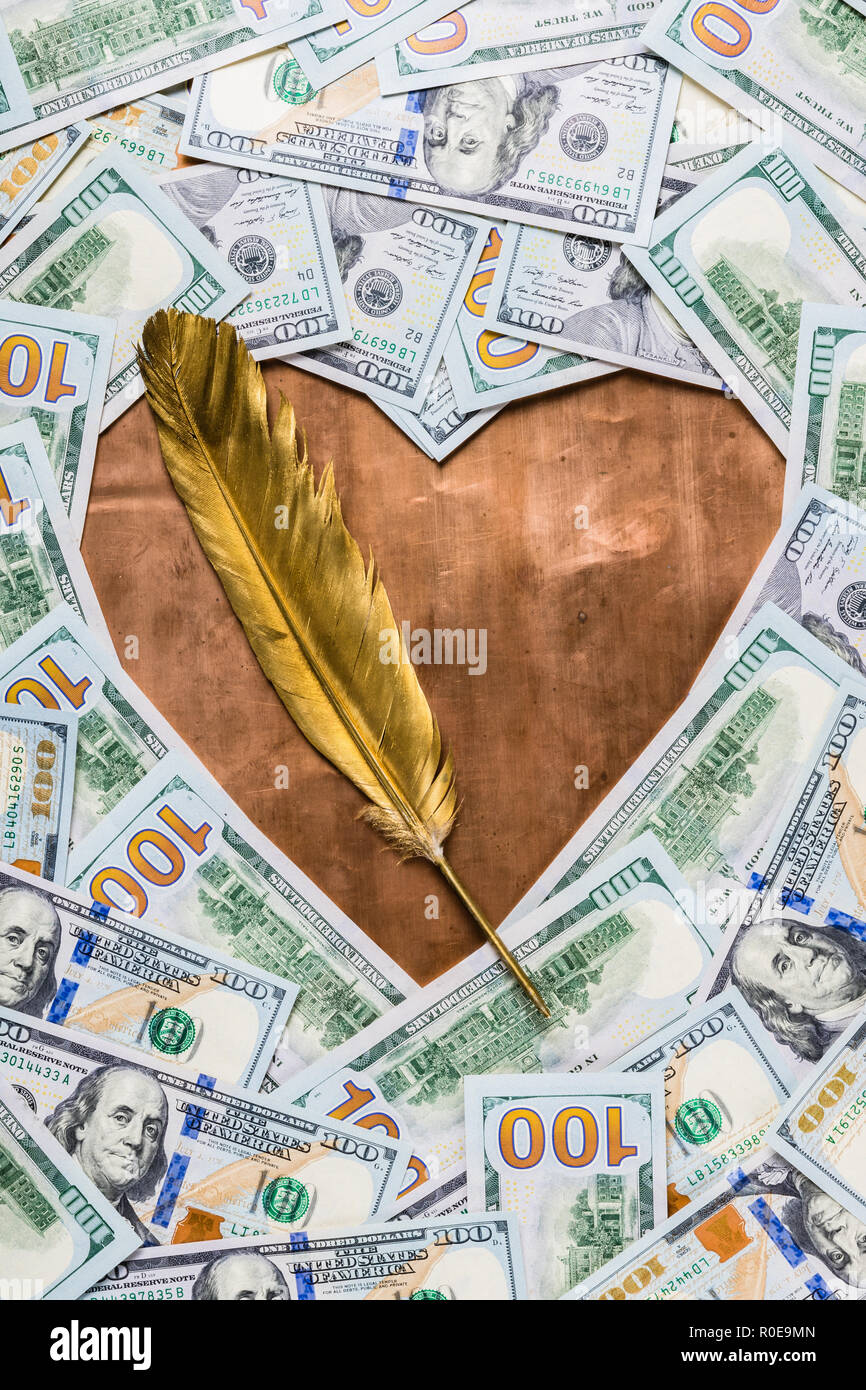 Bronzo rame forma di cuore e gold quill penna nel centro del dollaro sullo sfondo di denaro Foto Stock
