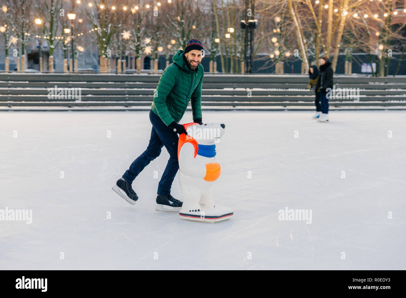 Positivo attraente sorridente uomo in caldo abbigliamento invernale e  pattini, prassi andare il pattinaggio su ghiaccio, utilizza il pattino  rink, guarda deliziosamente nella fotocamera, trascorrere Foto stock - Alamy