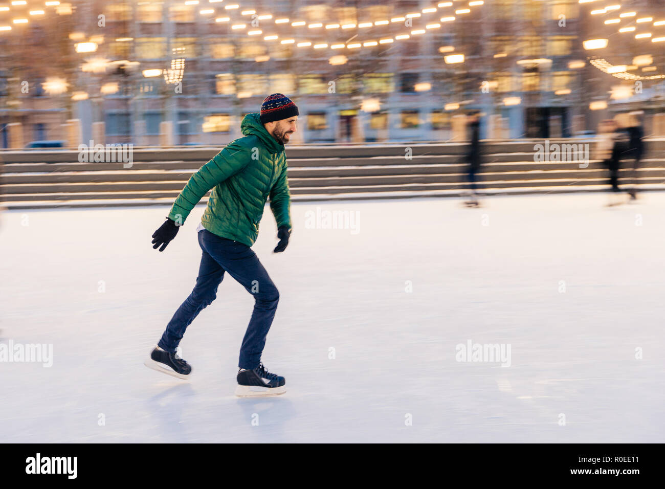 Di mezza età indossa maschio figura pattini, essendo al pattinaggio su ghiaccio in inverno park, ha divertimento con gli amici. Atleta pattinatore di velocità dimostra il suo talento sul pattinaggio Foto Stock