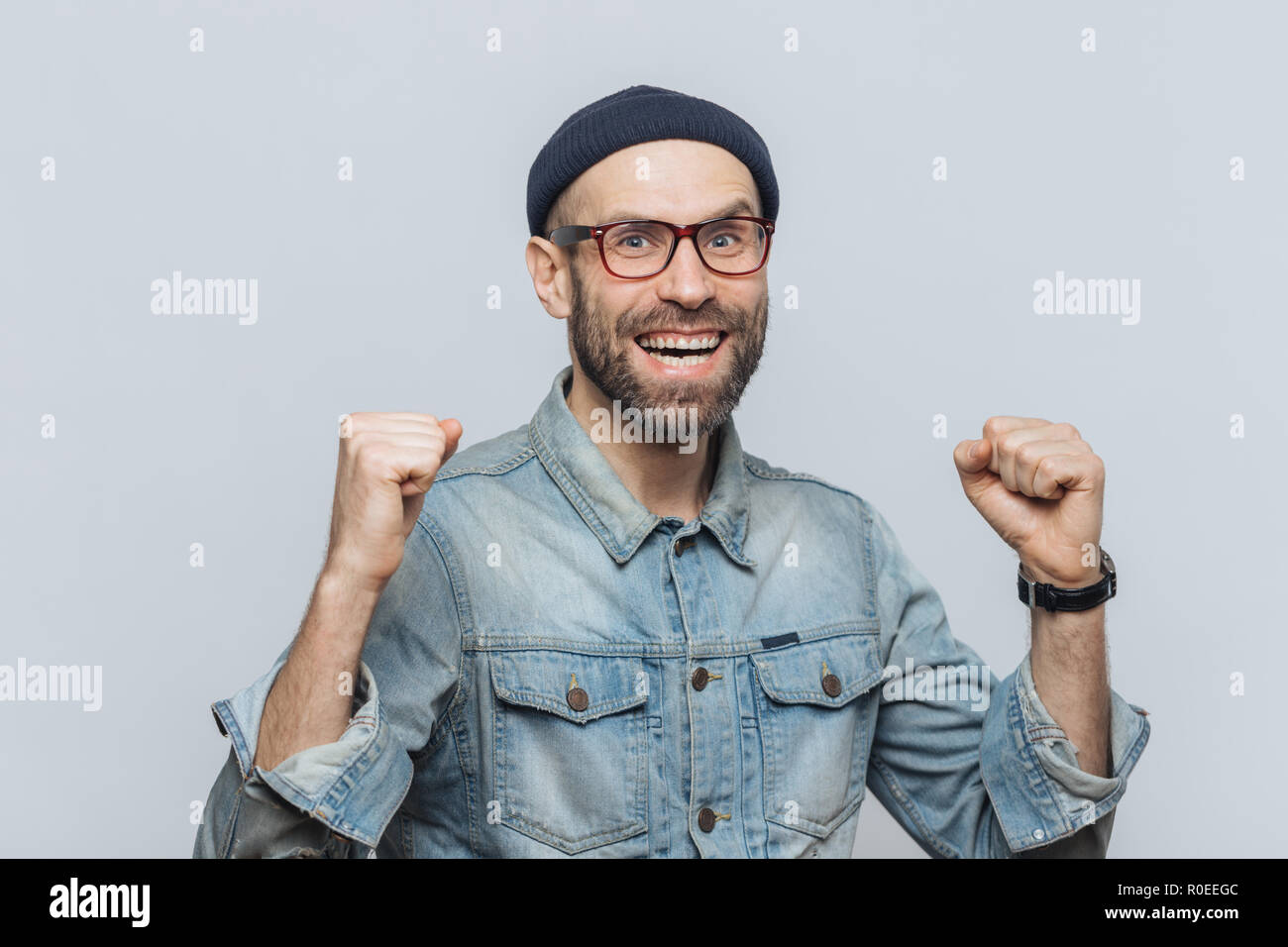 Ritratto di felice uomo di successo esulta il suo trionfo, clenches denti, ha detto contentissimo espressione, isolate su uno sfondo grigio. Bello di moda m Foto Stock