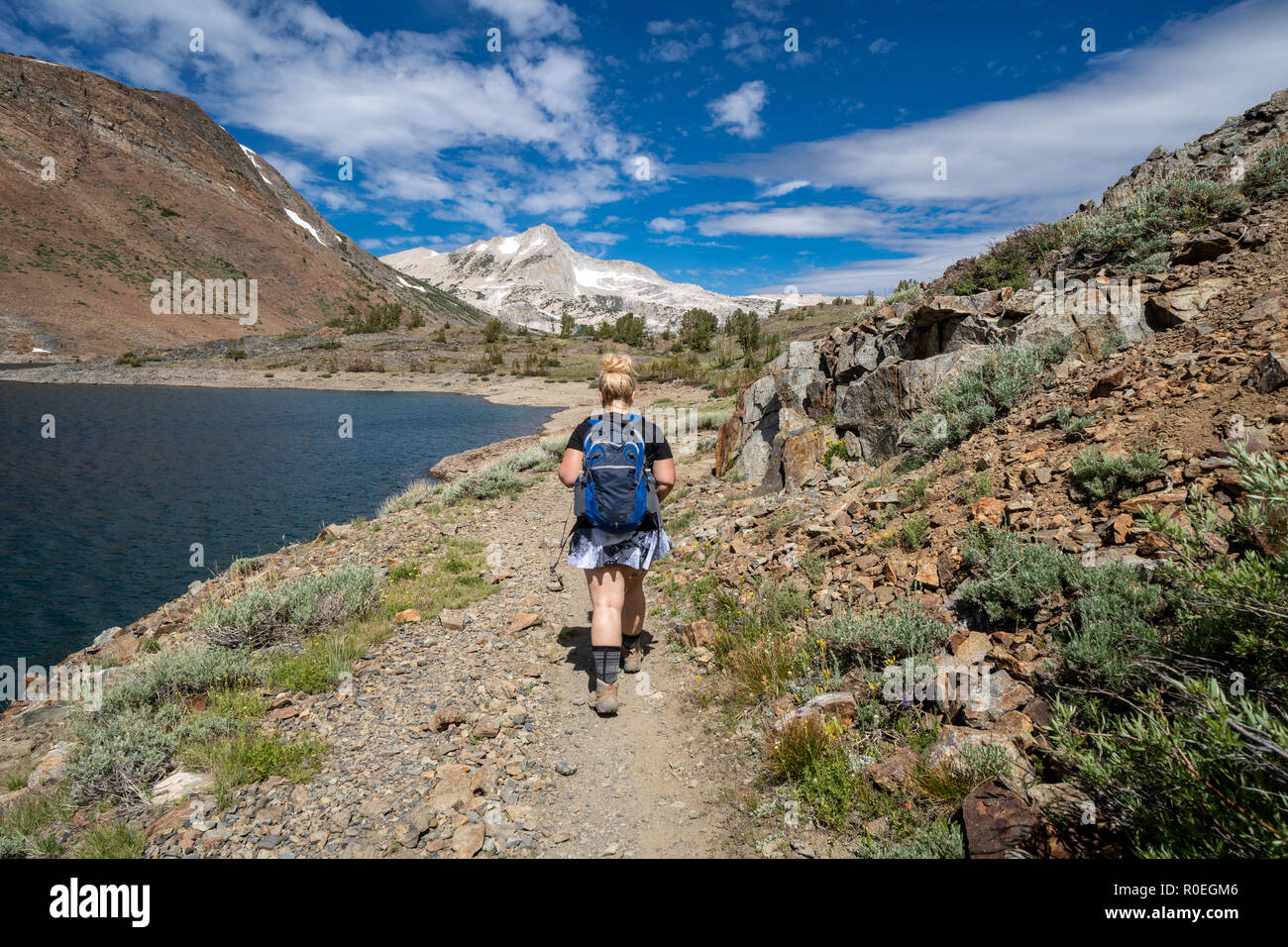 Montare la giovane donna escursionista backpacker su un sentiero nella parte orientale della Sierra Nevada. Concetto di wanderlust, perso, solo viaggio Foto Stock