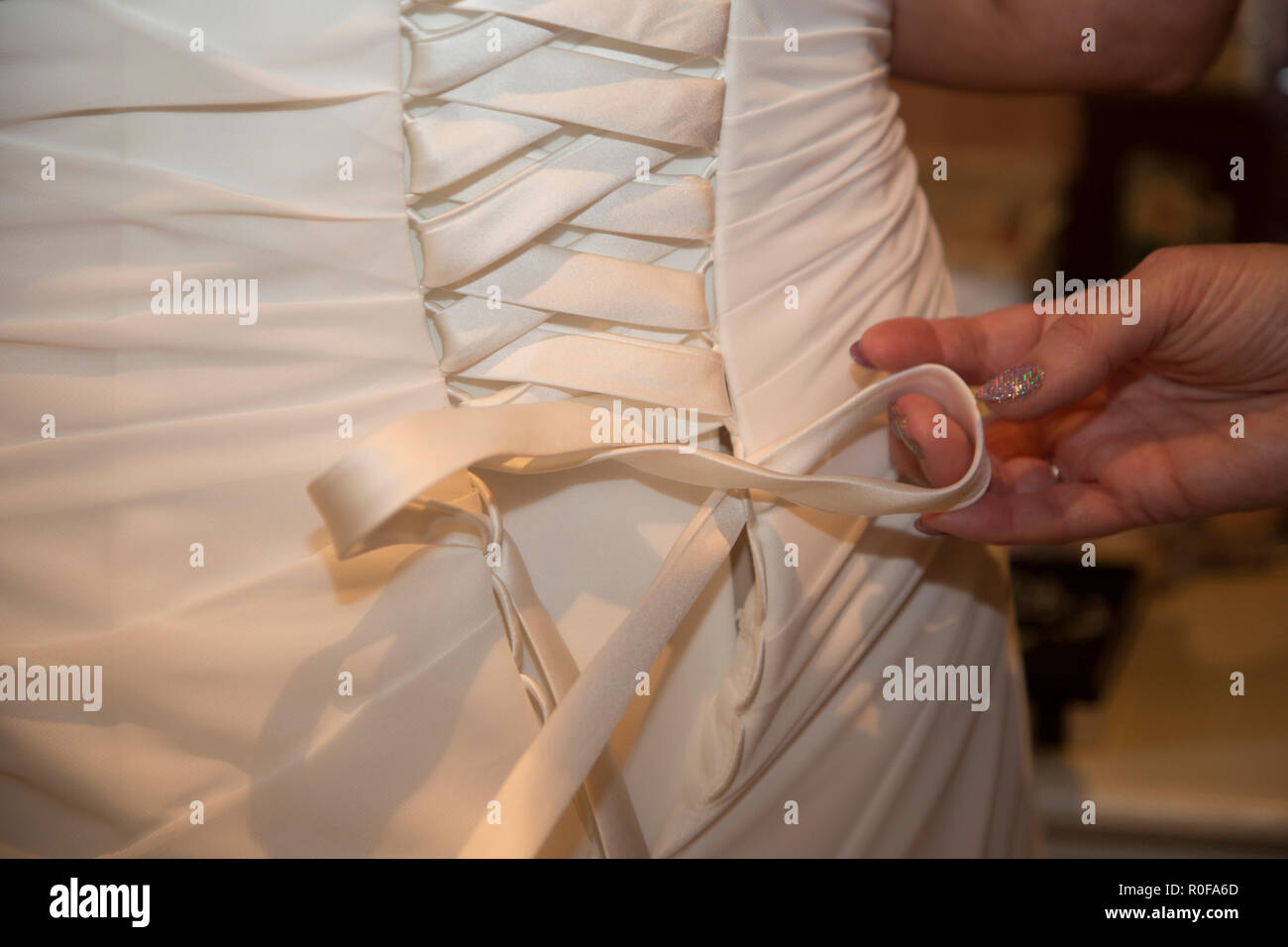 Close up di abiti da sposa di essere allacciato sul retro le spose il giorno del nostro matrimonio prima di lei ottiene sposato Foto Stock