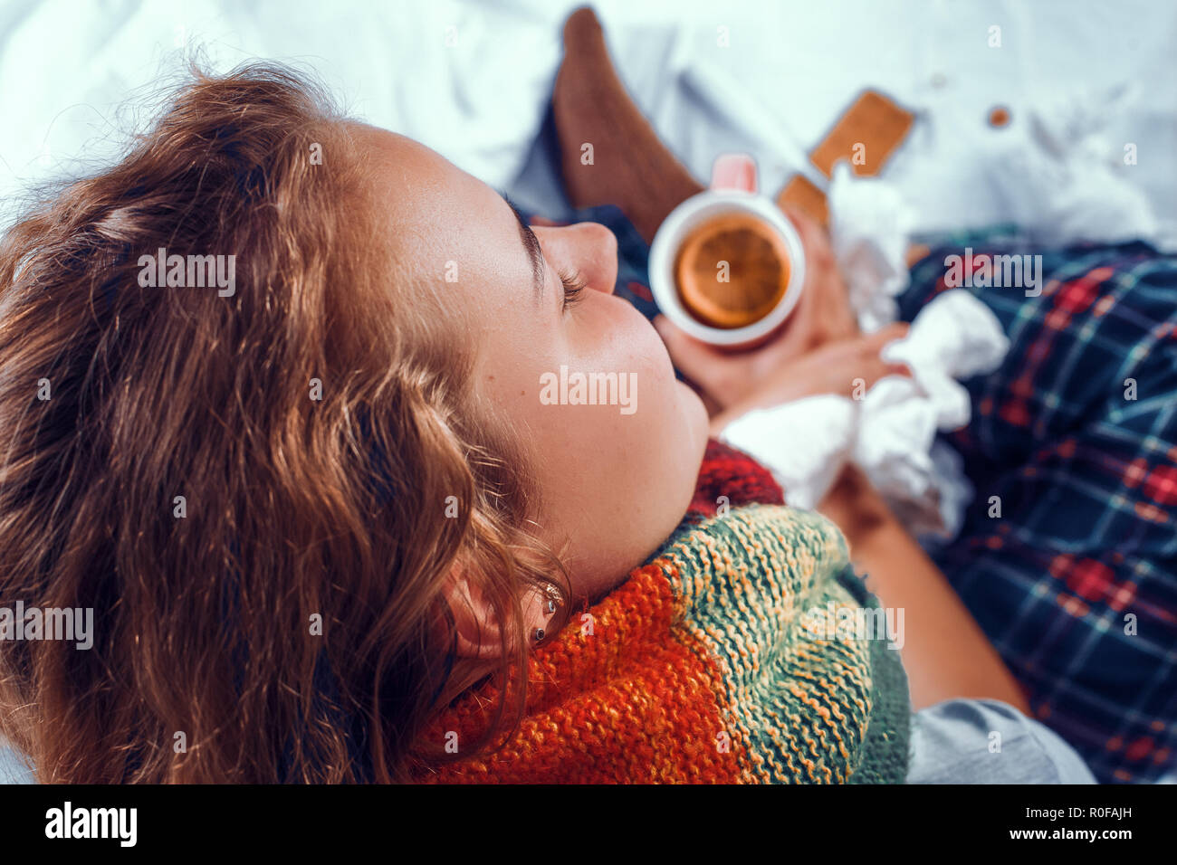 Vista da sopra su malata nel letto tenendo una tazza di tè con orange in esso Foto Stock