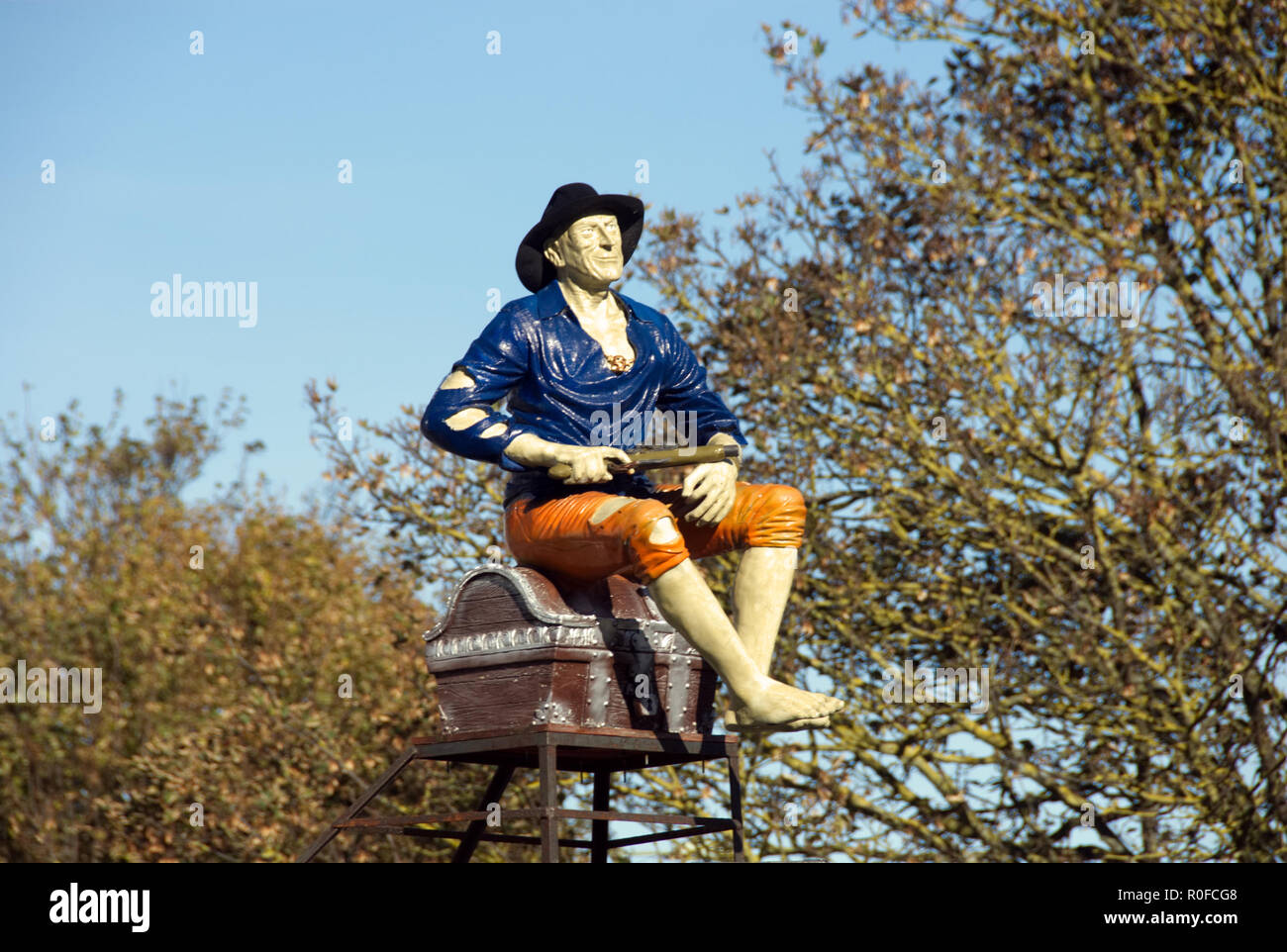 Modello di mal vestito uomo seduto sul tronco, con la pistola in mano, come "punto di vendita' vengono visualizzati al di fuori del negozio chiuso, Hayling Island in Inghilterra Foto Stock