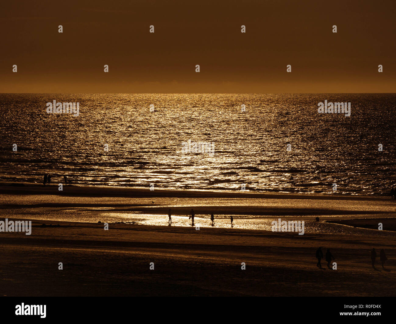 Vista da sopra verso una spiaggia dorata e acque scure appena prima del tramonto Foto Stock