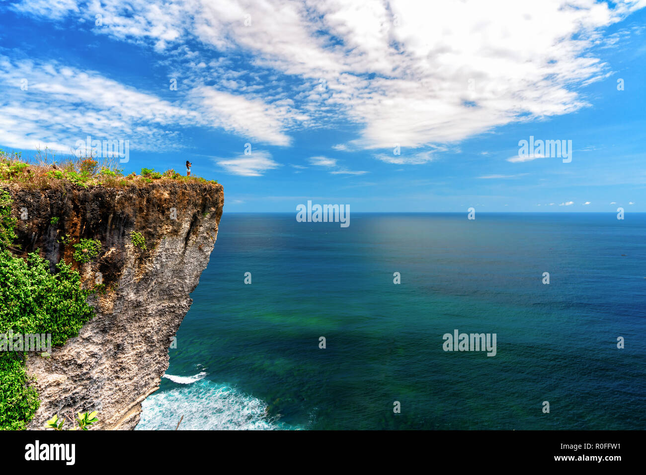 Giovane donna turistica è seduto sulla cima del fissaggio e guardando una bella baia mare paesaggio. Foto Stock
