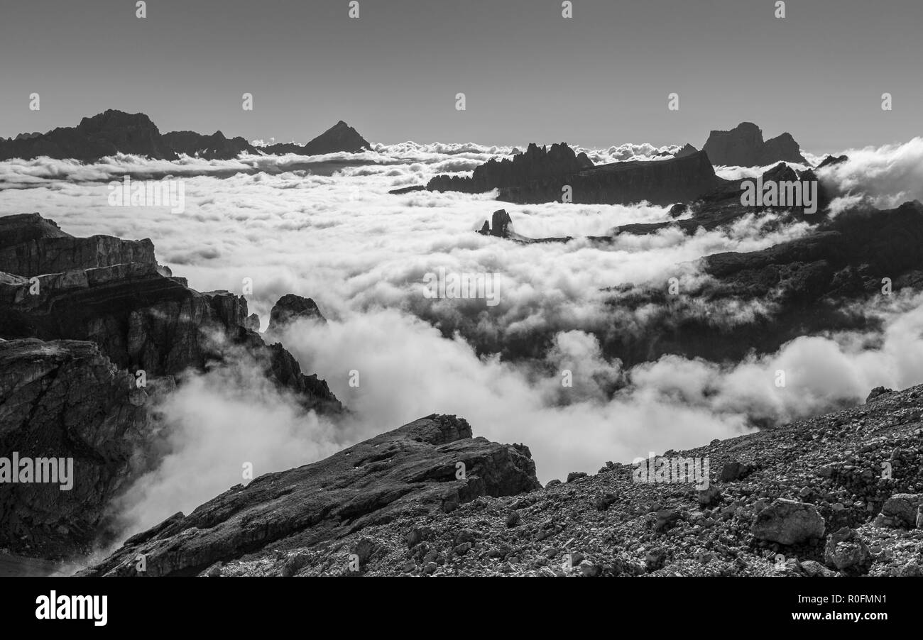 Marea di nuvole all'alba sulla Valle d'Ampezzo. Le Dolomiti. Alpi Italiane. Paesaggio di montagna bianco nero. Europa. Foto Stock