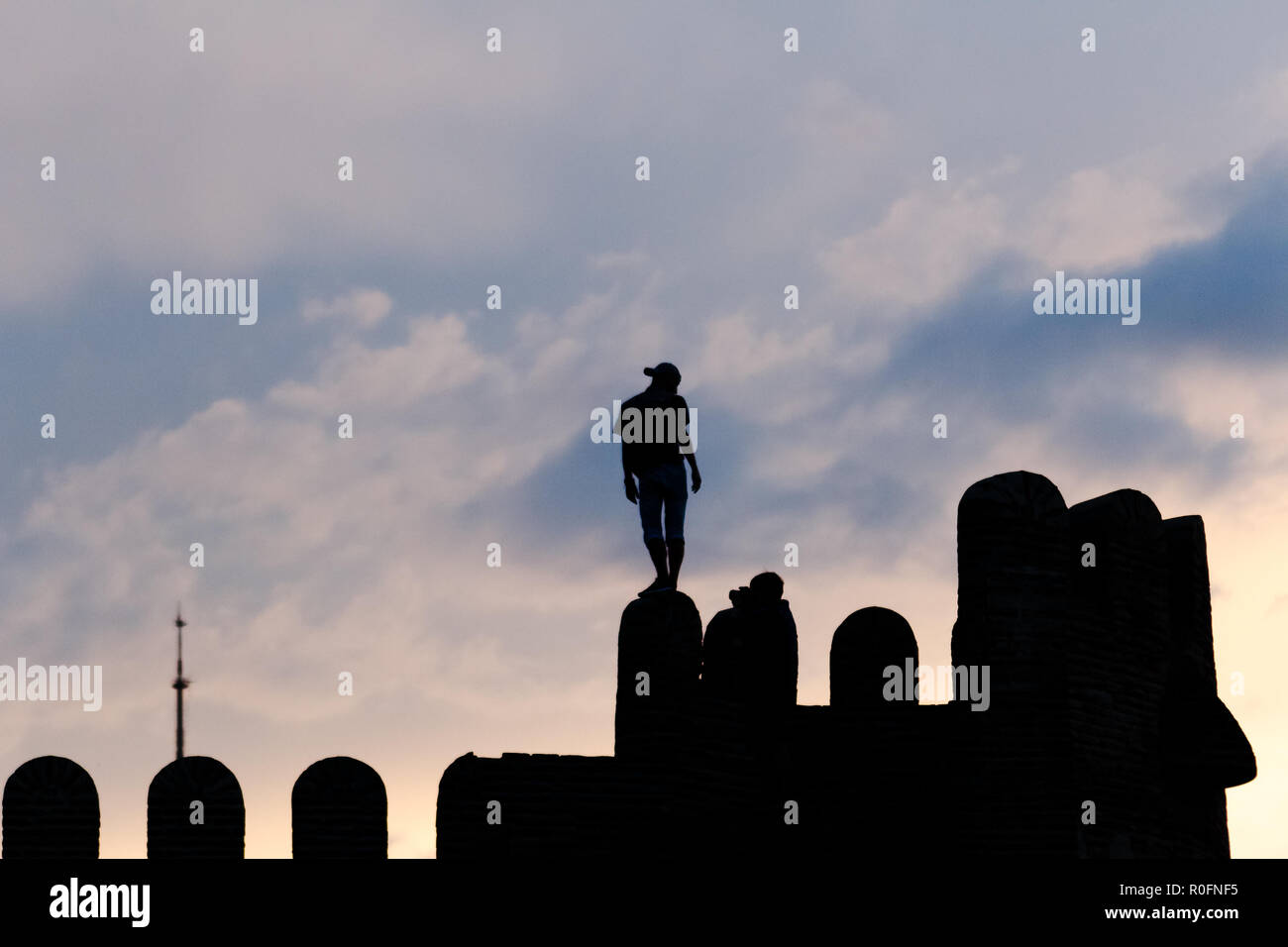 Parete della città di Tbilisi, Georgia al tramonto con silhouette di persone in piedi. Sfondo con cielo nuvoloso. Foto Stock