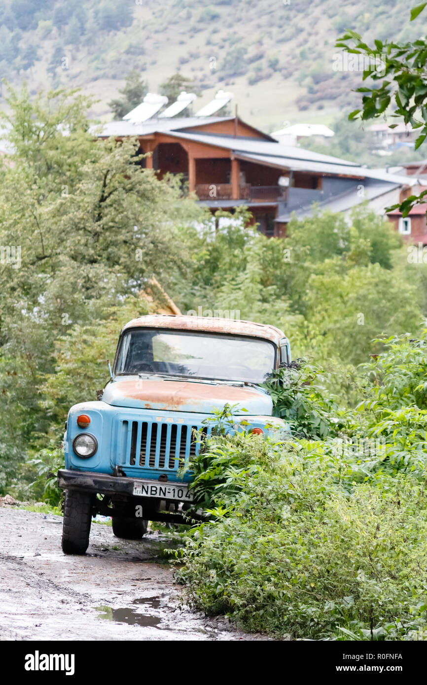 Vecchio Blu agricoli arrugginito carrello sovietica nel verde dei boschi nei pressi di strada nel villaggio di montagna, Mestia, Svaneti, Georgia Foto Stock