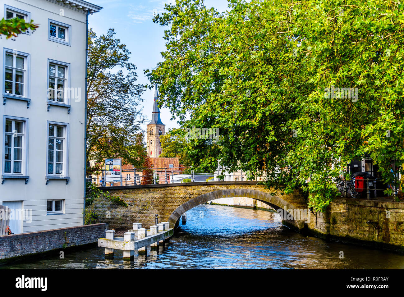 Il ponte di pietra a la Hoogstraat dalla Groenerei e Coupure canali di Bruges, Belgio con la Sant'Anna campanile di una chiesa in background Foto Stock