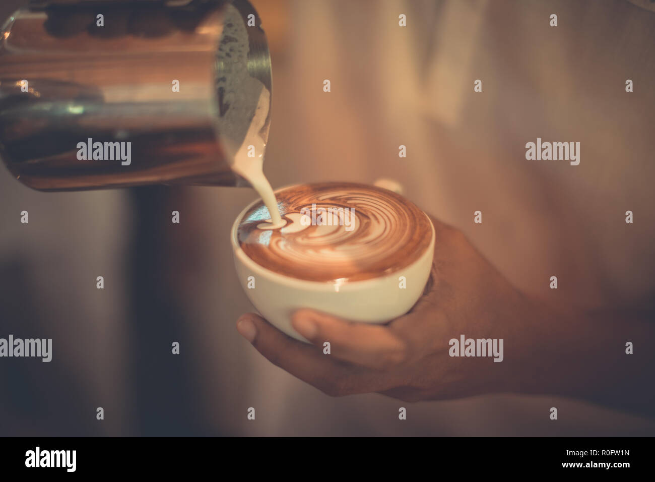 Arte a caldo latte caffè in una tazza sul tavolo di legno e la caffetteria di sfocatura con sfondo bokeh di fondo dell'immagine. Latte Art tavolino vista superiore, felice atmosfera rilassante Foto Stock