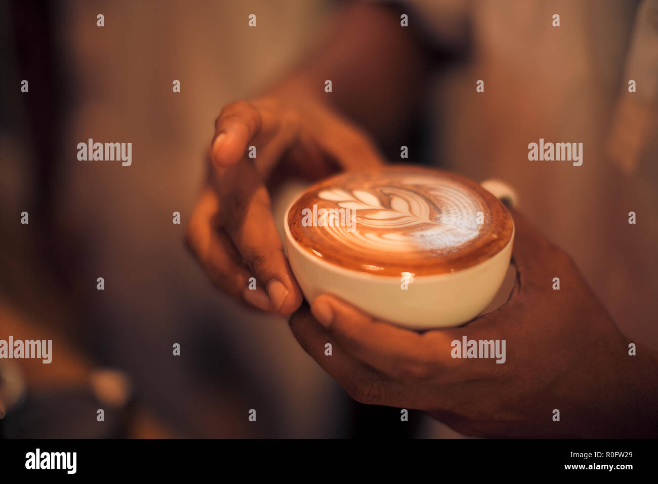 Arte a caldo latte caffè in una tazza sul tavolo di legno e la caffetteria di sfocatura con sfondo bokeh di fondo dell'immagine. Latte Art tavolino vista superiore, felice atmosfera rilassante Foto Stock
