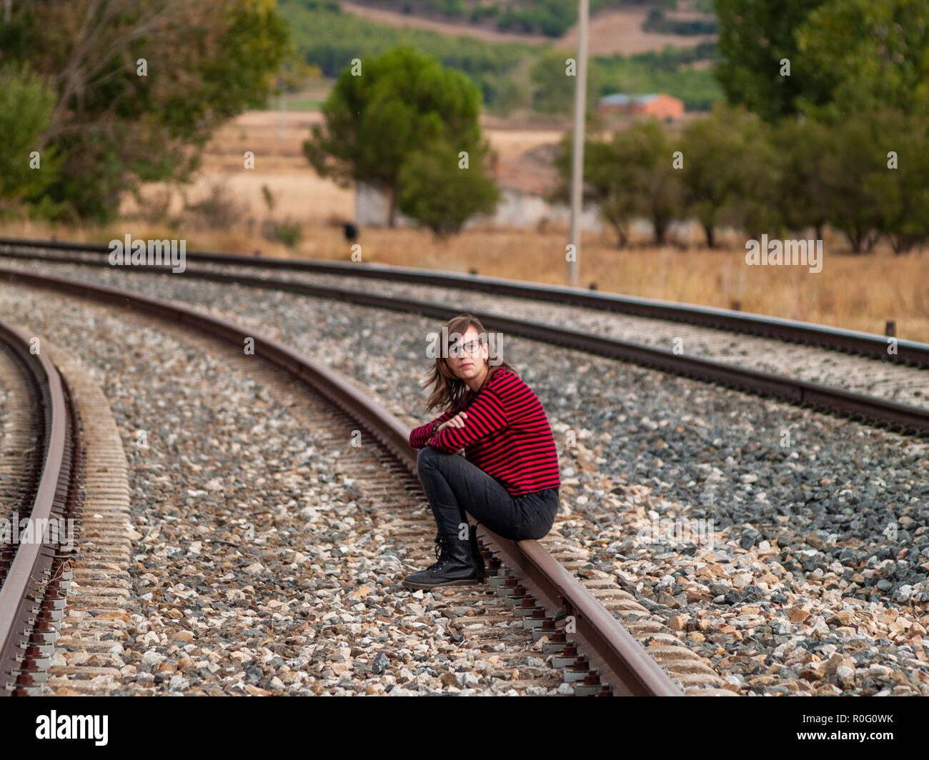 Un solitario teen ragazza seduta sui binari del treno Foto Stock